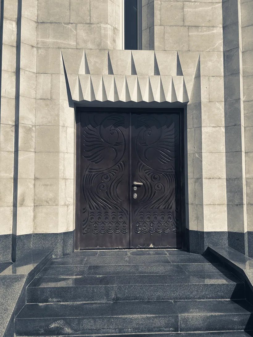 Les portes de bois sculpté du temple Quba Mêrê Dîwanê, au sommet de quelques marches de pierre.